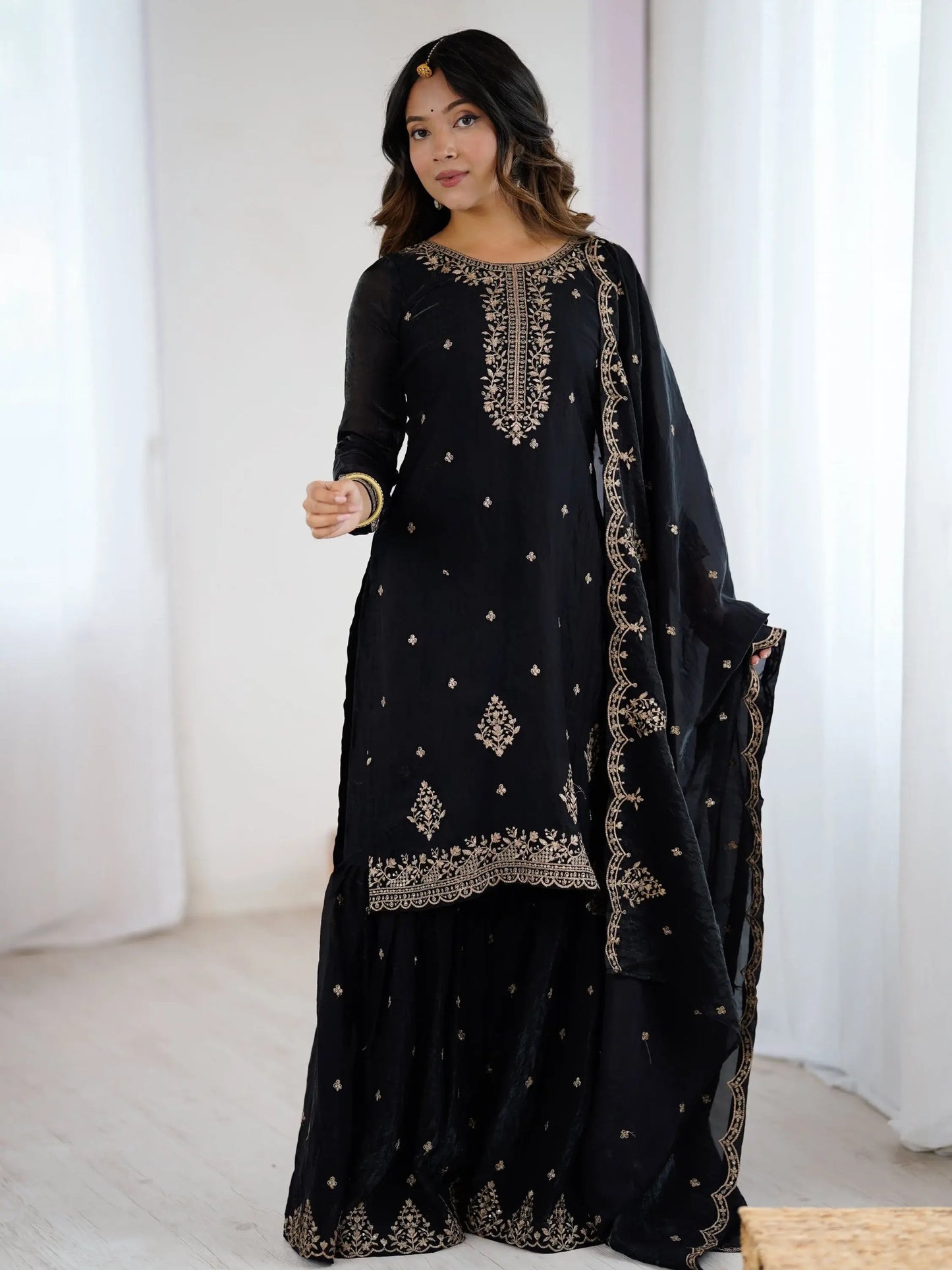 Schwarzes Sharara-Set aus Seide mit goldener Zari-Stickerei, bestehend aus Top, weiter Sharara-Hose und Dupatta – festliche indische Damenmode.