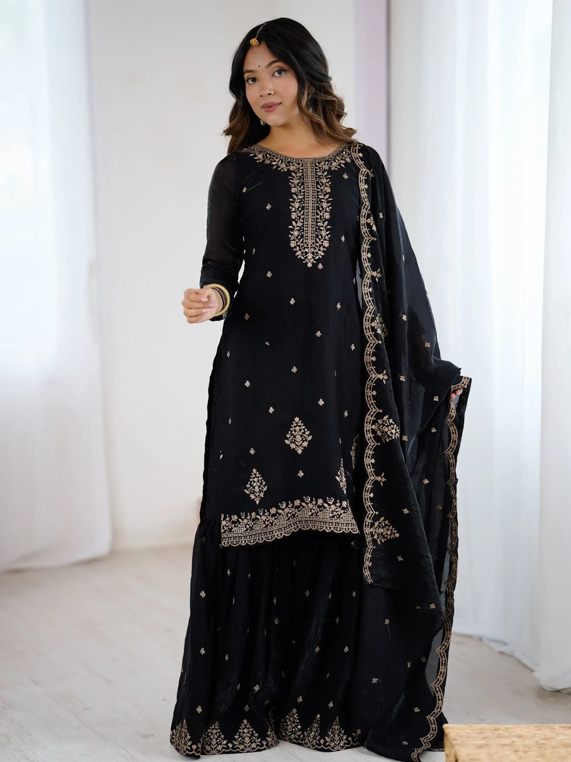 Schwarzes Sharara-Set aus Seide mit goldener Zari-Stickerei, bestehend aus Top, weiter Sharara-Hose und Dupatta – festliche indische Damenmode.