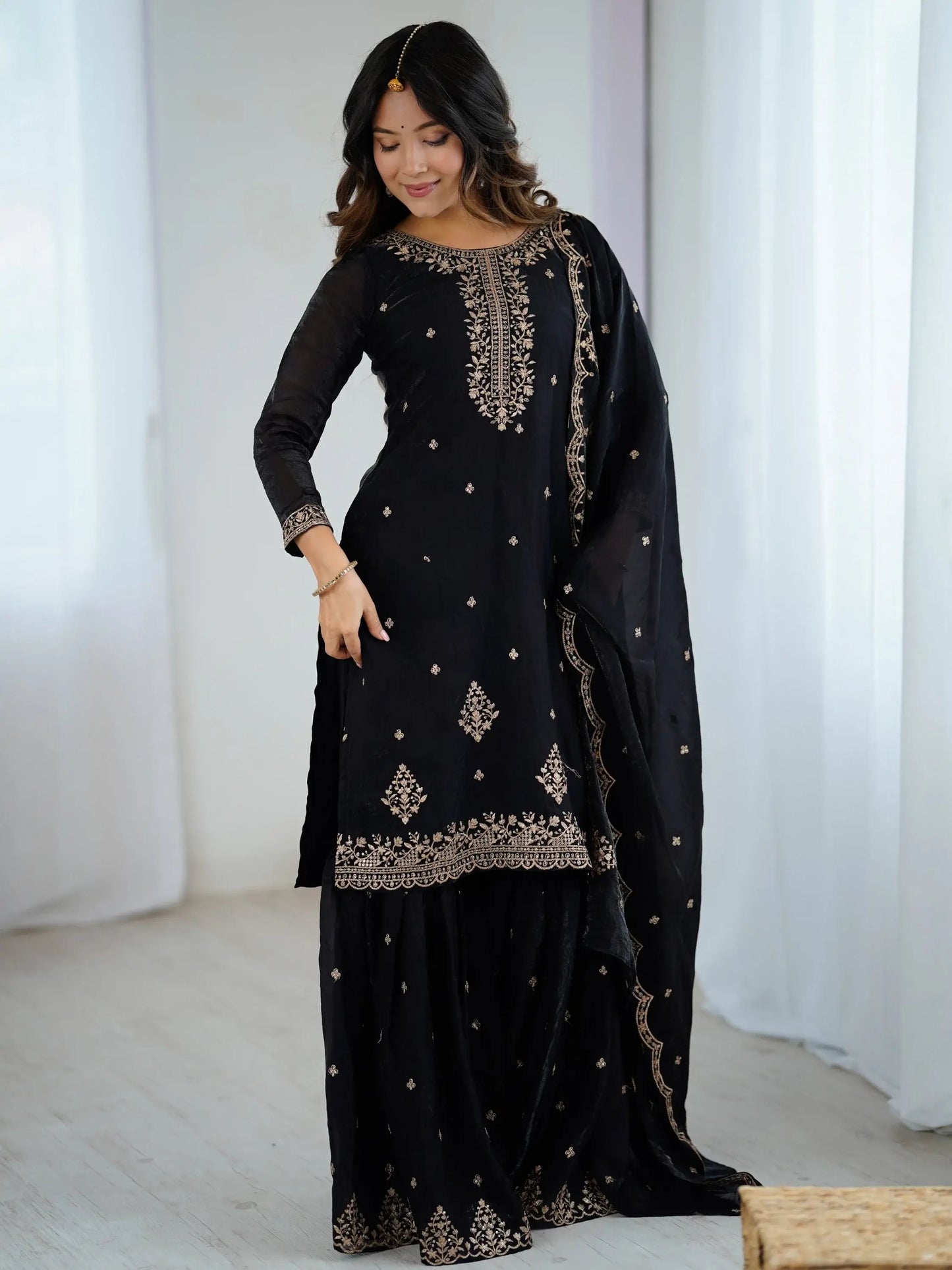 Schwarzes Sharara-Set aus Seide mit goldener Zari-Stickerei, bestehend aus Top, weiter Sharara-Hose und Dupatta – festliche indische Damenmode.