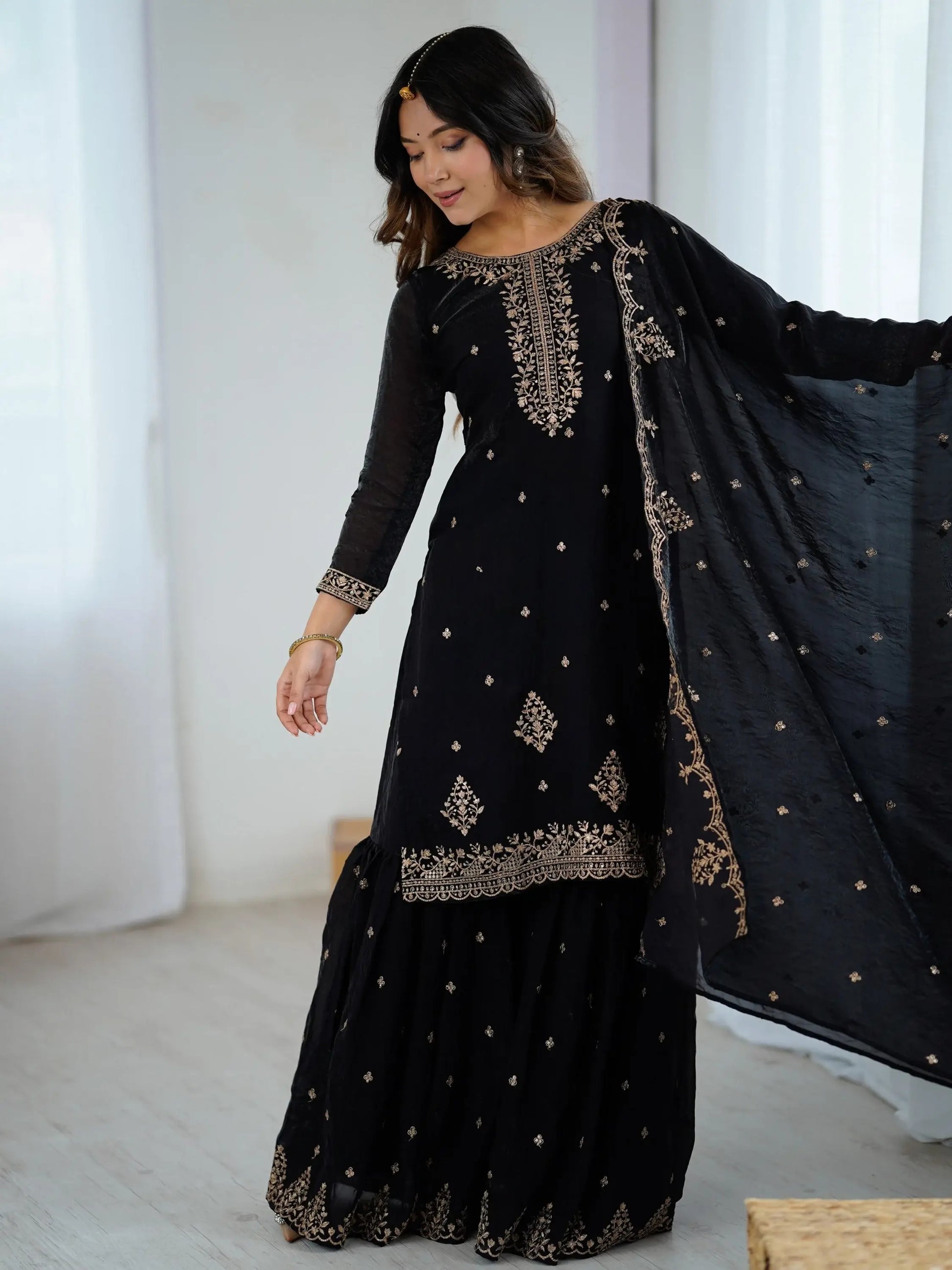 Schwarzes Sharara-Set aus Seide mit goldener Zari-Stickerei, bestehend aus Top, weiter Sharara-Hose und Dupatta – festliche indische Damenmode.