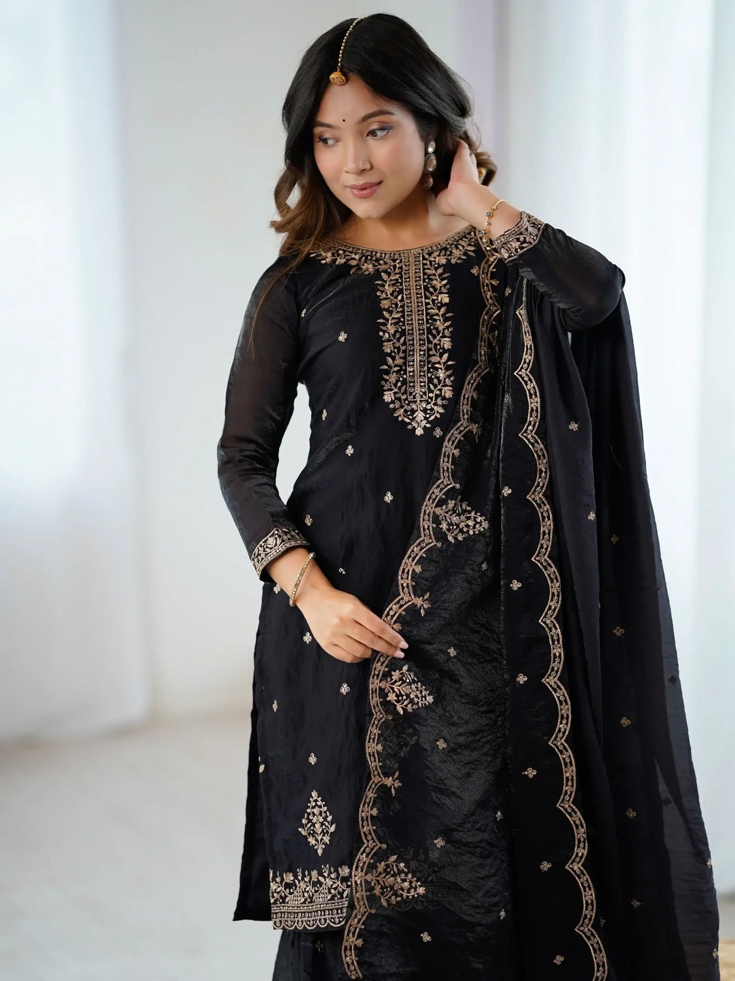 Schwarzes Sharara-Set aus Seide mit goldener Zari-Stickerei, bestehend aus Top, weiter Sharara-Hose und Dupatta – festliche indische Damenmode.