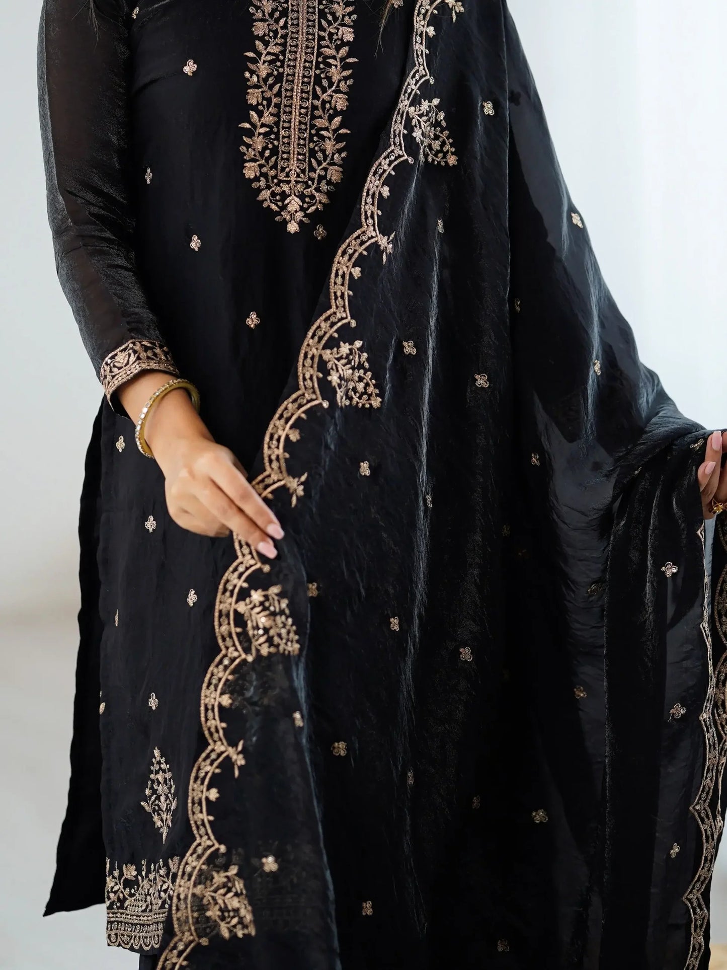 Schwarzes Sharara-Set aus Seide mit goldener Zari-Stickerei, bestehend aus Top, weiter Sharara-Hose und Dupatta – festliche indische Damenmode.